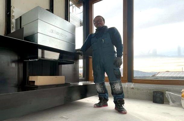Portrait des Ofenbaumeisters auf der Baustelle neben einer eingebauten Feuerstätte